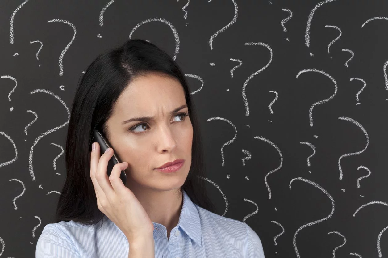woman holding mobile phone to her ear looking puzzled.